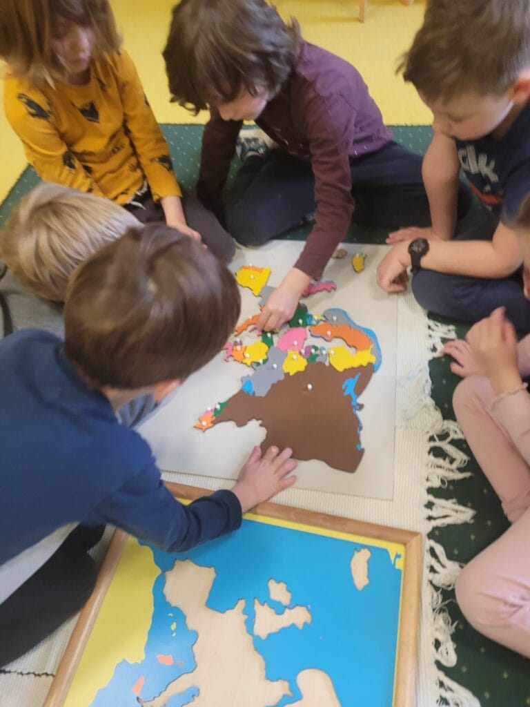 Kilkoro dzieci pracuje wspólnie nad mapą świata