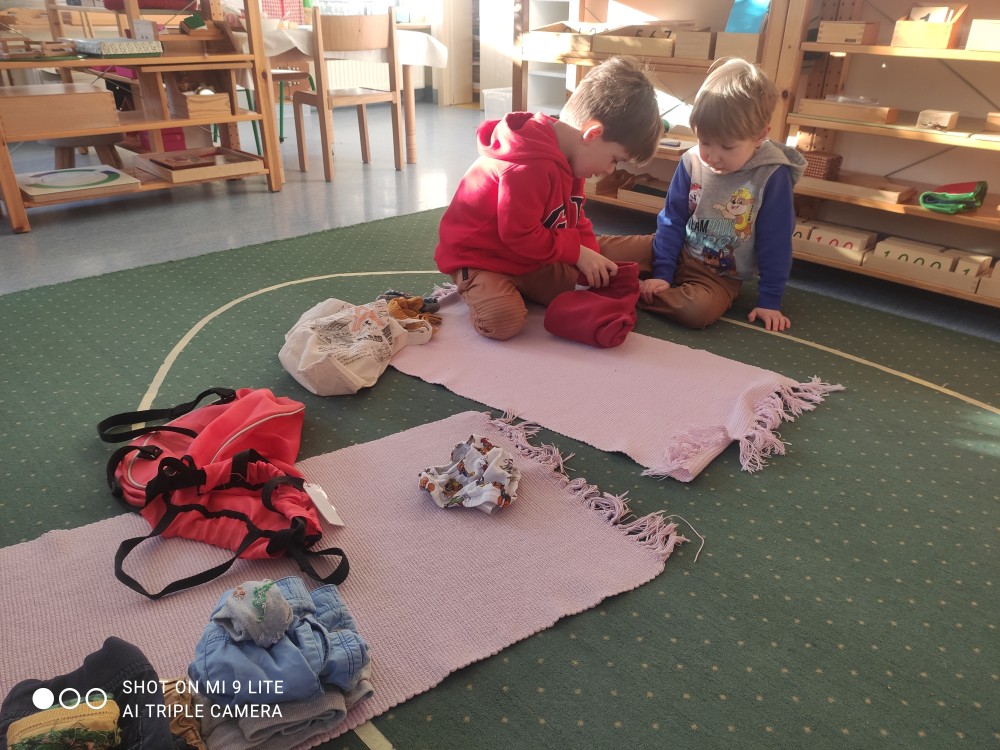 Starsze dziecko uczy młodszego przedszkolaka składania
ubrań podczas codziennych zajęć w przedszkolu