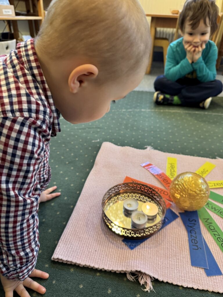 Grupa przedszkolaków świętuje urodziny kolegi, dziecko
zdmuchuje urodzinowe świeczki:)