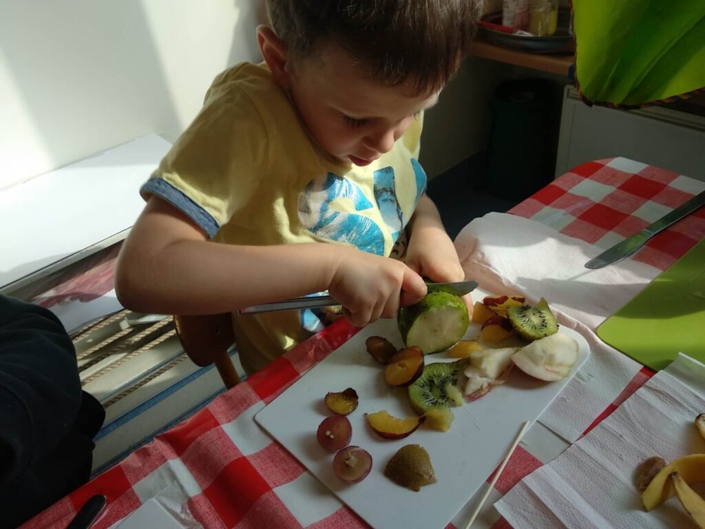 Czteroletni Tomek kroi banana nożem stołowym. 